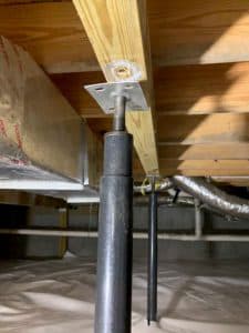 Steel jack installed under wooden beam